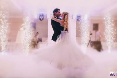 Un couple danse au centre d'une salle élégamment décorée, entouré de lumière et d'effets de fumée.