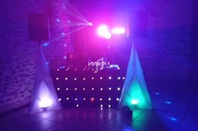 Installation de DJ avec lumières colorées et effets lumineux dans une salle aux murs en pierre.