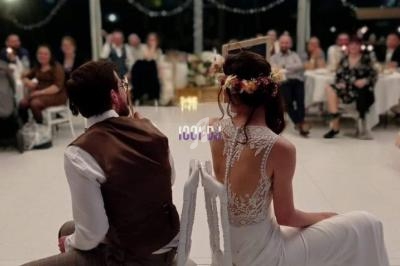 Un couple assis dos à dos sur des chaises dans une salle de réception lumineuse, entouré d'invités.