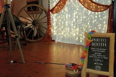 Décor de photobooth avec rideau lumineux, pancarte en bois, accessoires colorés et inscription ’Just Married’.