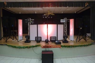 Scène décorée avec des équipements de son et lumière, incluant des projecteurs et des enceintes, prête pour un événement.