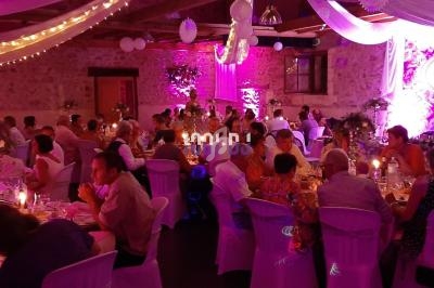Salle de réception décorée avec des guirlandes lumineuses et des invités assis à des tables lors d'un mariage.