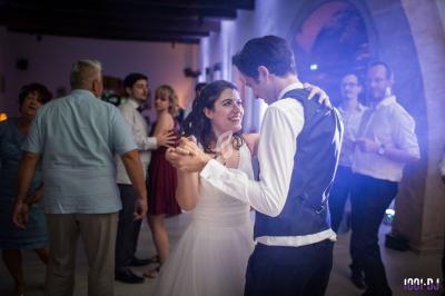 Un couple danse lors d'une réception, entouré d'invités dans une salle éclairée de lumières tamisées.