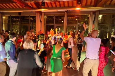 Groupe de personnes dansant dans une salle éclairée par des lumières chaudes, ambiance festive en soirée.