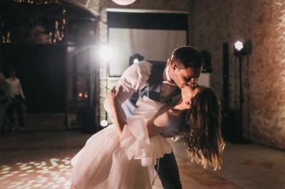 Un couple danse dans une salle faiblement éclairée, l'homme inclinant la femme pour un baiser.