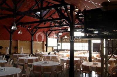 Bâtiment en bois avec une clôture métallique et un panneau indiquant ’La Forge’, entouré de végétation.