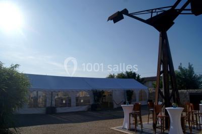 Bâtiment en bois avec une clôture métallique et un panneau indiquant ’La Forge’, entouré de végétation.