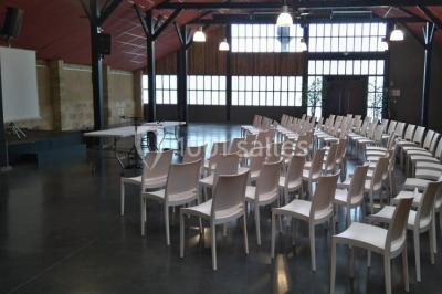 Bâtiment en bois avec une clôture métallique et un panneau indiquant ’La Forge’, entouré de végétation.