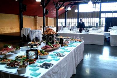 Bâtiment en bois avec une clôture métallique et un panneau indiquant ’La Forge’, entouré de végétation.