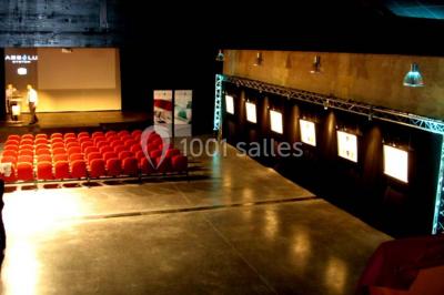 Bâtiment en bois avec une clôture métallique et un panneau indiquant ’La Forge’, entouré de végétation.