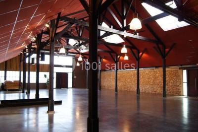 Bâtiment en bois avec une clôture métallique et un panneau indiquant ’La Forge’, entouré de végétation.