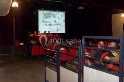 Bâtiment en bois avec une clôture métallique et un panneau indiquant ’La Forge’, entouré de végétation.