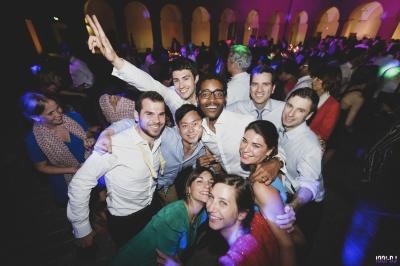 Groupe de personnes souriantes posant ensemble lors d'une soirée animée avec éclairage coloré.