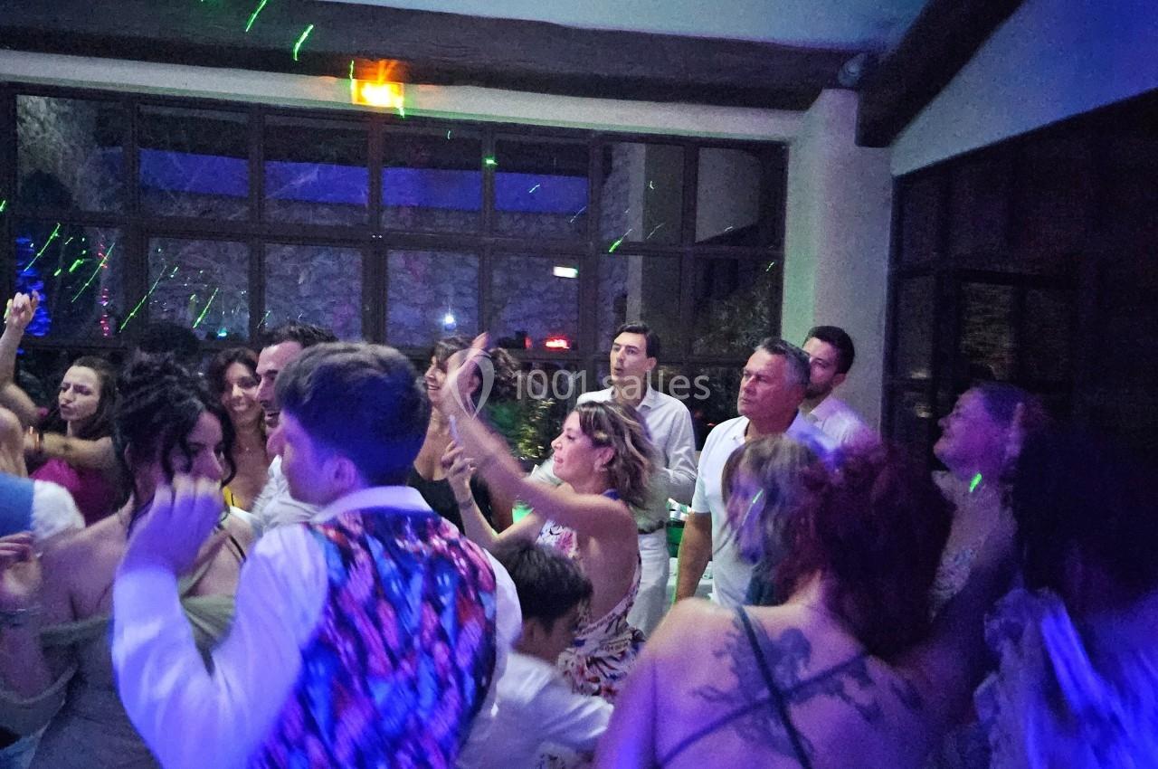 Groupe de personnes dansant dans une salle sombre avec des lumières colorées et une ambiance festive.