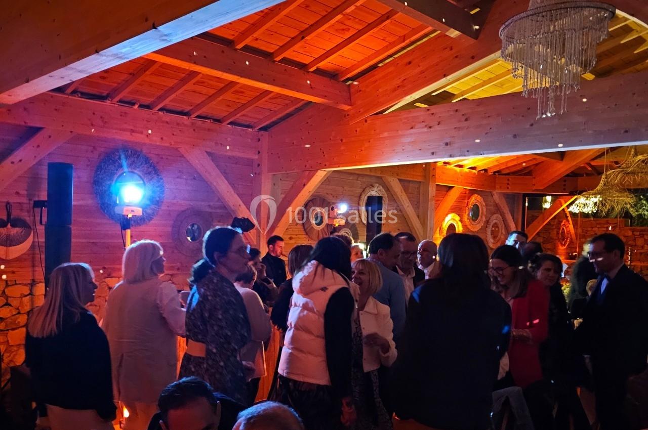 Groupe de personnes discutant dans une salle en bois éclairée par des lumières chaudes.