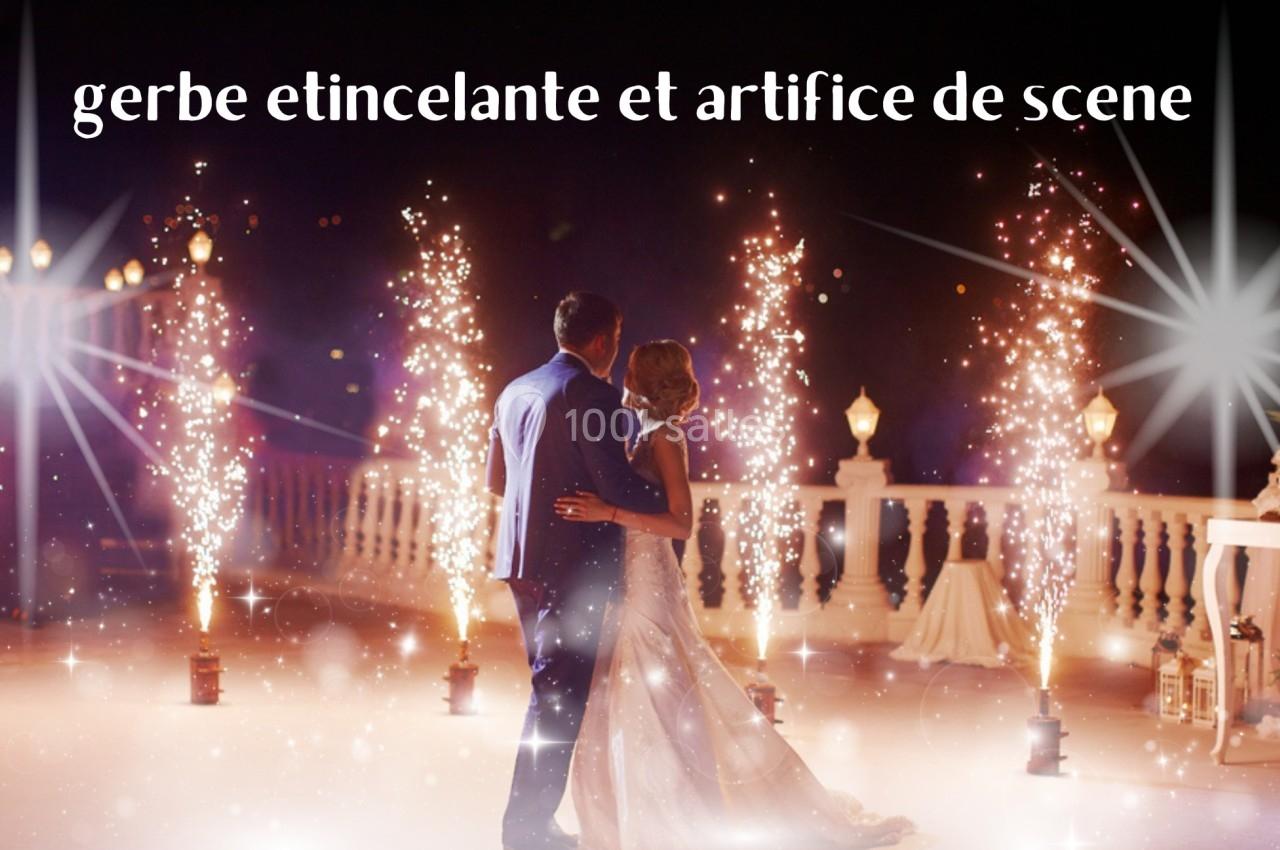 Un couple de dos dansant devant des gerbes d'étincelles et des décorations lumineuses en extérieur la nuit.