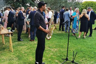 Quatre musiciens en costume jouent de la guitare et du cajón en extérieur lors d'un événement.