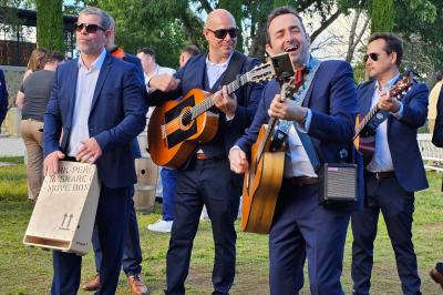 Quatre musiciens en costume jouent de la guitare et du cajón en extérieur lors d'un événement.