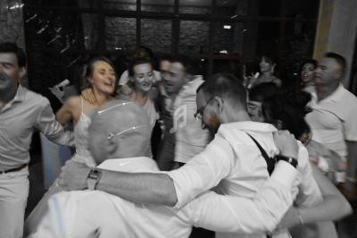 Un groupe de personnes dansant en cercle lors d'une fête, souriants et bras entrelacés.