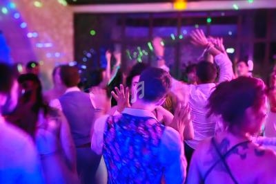 Personnes dansant sous des lumières colorées dans une ambiance festive à l'intérieur d'une salle.