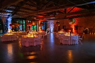 Salle de réception décorée avec des tables rondes, éclairage chaleureux et lanternes suspendues.