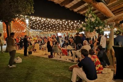 Groupe de personnes réunies en soirée sous des guirlandes lumineuses dans un espace extérieur couvert.
