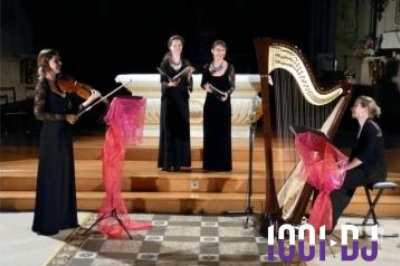 Une violoncelliste joue lors d'une cérémonie dans une église, entourée d'invités debout et de mariés à l'arrière-plan.