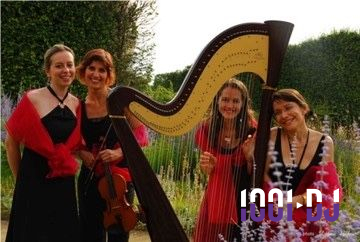 Une violoncelliste joue lors d'une cérémonie dans une église, entourée d'invités debout et de mariés à l'arrière-plan.