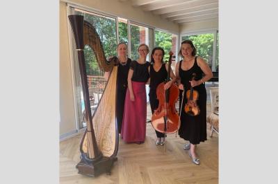 Une violoncelliste joue lors d'une cérémonie dans une église, entourée d'invités debout et de mariés à l'arrière-plan.