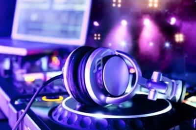 Casque audio posé sur une platine de DJ, éclairé par des lumières violettes dans une ambiance de concert.