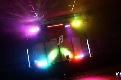 Jeu de lumières colorées sur une scène sombre avec des équipements de sonorisation en arrière-plan.