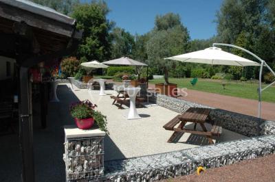 Vue d'un étang entouré d'arbres et de végétation sous un ciel partiellement nuageux.
