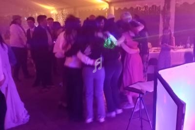 Groupe de personnes dansant en cercle sous une tente éclairée de lumières colorées lors d'un événement festif.