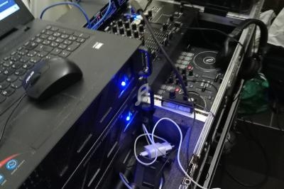 Équipement de DJ comprenant une console de mixage, un ordinateur portable, des micros et des câbles connectés.