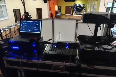 Équipement de DJ avec platines, table de mixage et ordinateur dans une salle aménagée pour un événement.