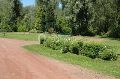 Vue d'un étang entouré d'arbres et de végétation sous un ciel partiellement nuageux.