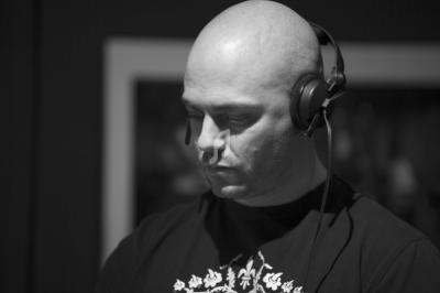 Homme chauve portant un casque audio, concentré, dans un environnement intérieur en noir et blanc.