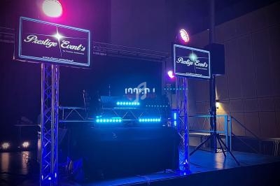 Installation de matériel de sonorisation et d'éclairage avec écrans affichant ’Prestige Event's’ dans une salle sombre.