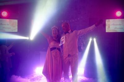 Un couple danse sous des lumières colorées et des effets de fumée dans une ambiance festive.