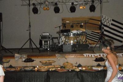 Buffet varié en premier plan avec une scène équipée de matériel musical et un drapeau breton en arrière-plan.