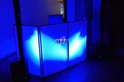 Console de DJ éclairée par une lumière bleue dans une pièce sombre avec des éléments de décoration en arrière-plan.