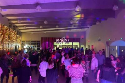 Groupe de personnes dans une salle éclairée par des lumières colorées, participant à une soirée dansante.