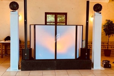 Installation de matériel de sonorisation et d'éclairage avec une cabine de DJ dans une salle intérieure.