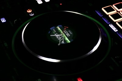 Bouton rotatif lumineux d'une console de mixage DJ avec un écran central affichant des informations audio.