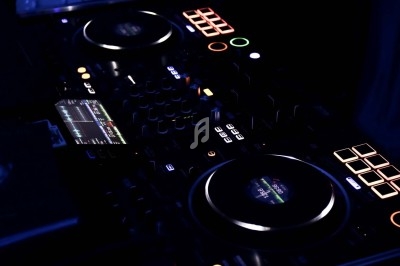 Deux platines DJ rétroéclairées avec des boutons lumineux et un écran affichant des informations audio.