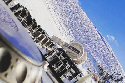 Table de mixage et casque audio en gros plan, avec un paysage enneigé et un ciel bleu en arrière-plan.