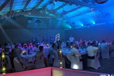 Salle de réception illuminée en bleu avec des invités assis à des tables rondes lors d'un événement festif.