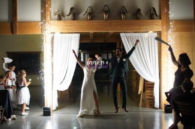 Un couple de mariés danse joyeusement sous des étincelles, entouré d'invités dans une salle décorée.
