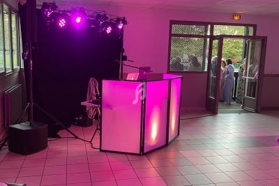 Installation de DJ avec éclairage violet dans une salle carrelée, des invités visibles à l'extérieur par une porte ouverte.