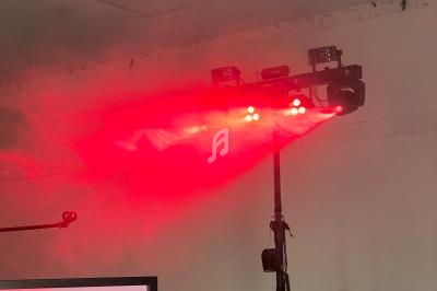 Projecteur LED rouge diffusant de la lumière et de la fumée dans une pièce au plafond blanc.